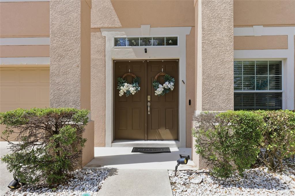 A front entrance with double brown doors, a transom window, and two small shrubs — 12515 SAWGRASS OAK STREET, ORLANDO, FL