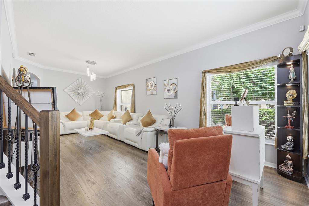 A living room features light gray walls, wood-look flooring, a white sectional sofa, and a recliner — 12515 SAWGRASS OAK STREET, ORLANDO, FL