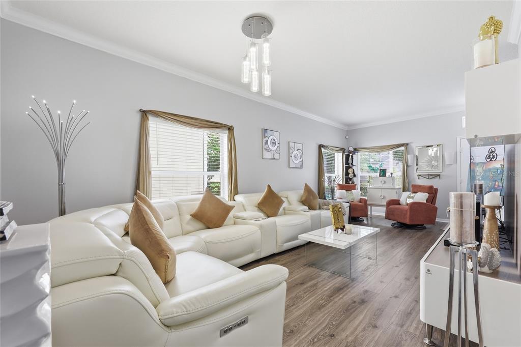 A living room features a white sectional sofa, wood-look flooring, and a modern light fixture — 12515 SAWGRASS OAK STREET, ORLANDO, FL