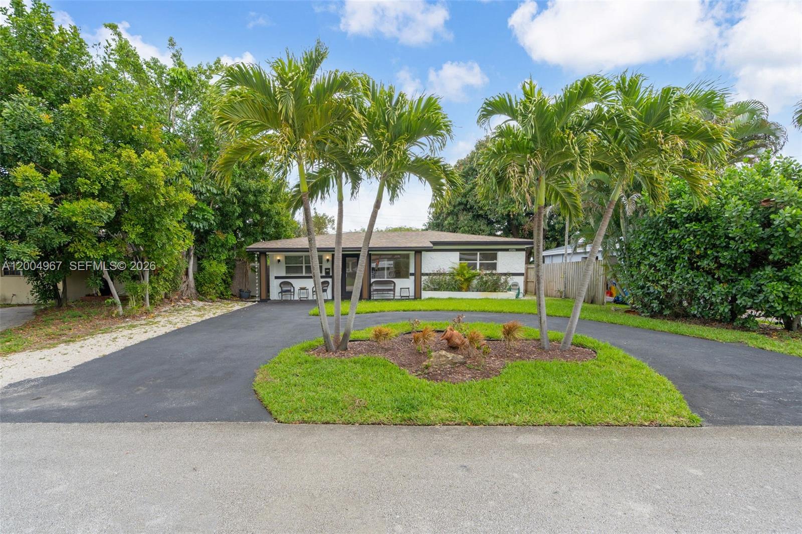 A single-story house features a circular driveway, palm trees, and a landscaped front yard — OAKLAND PARK, FL