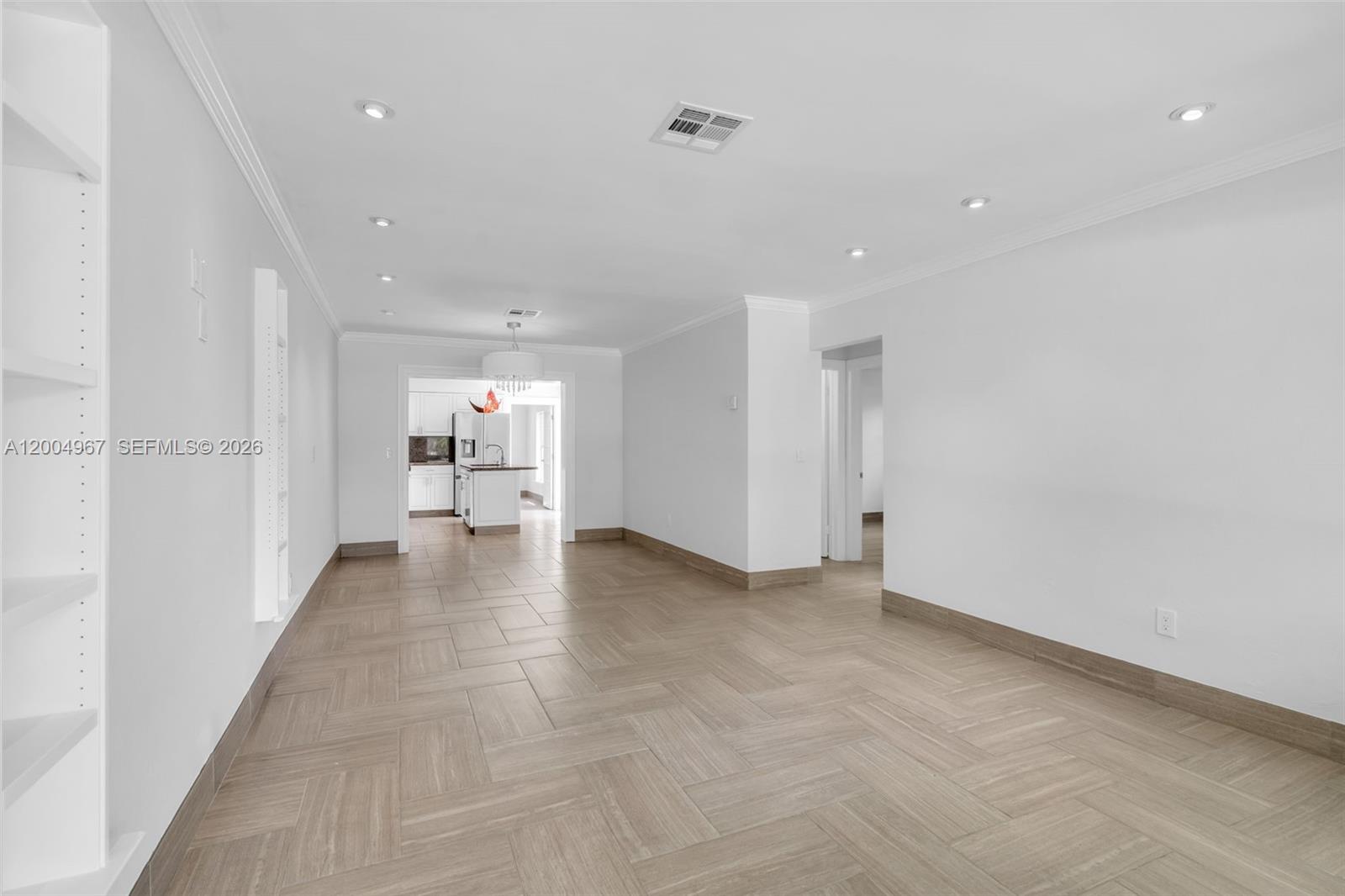 An empty room features light-colored tile flooring, white walls, recessed lighting, and built-in shelving — OAKLAND PARK, FL
