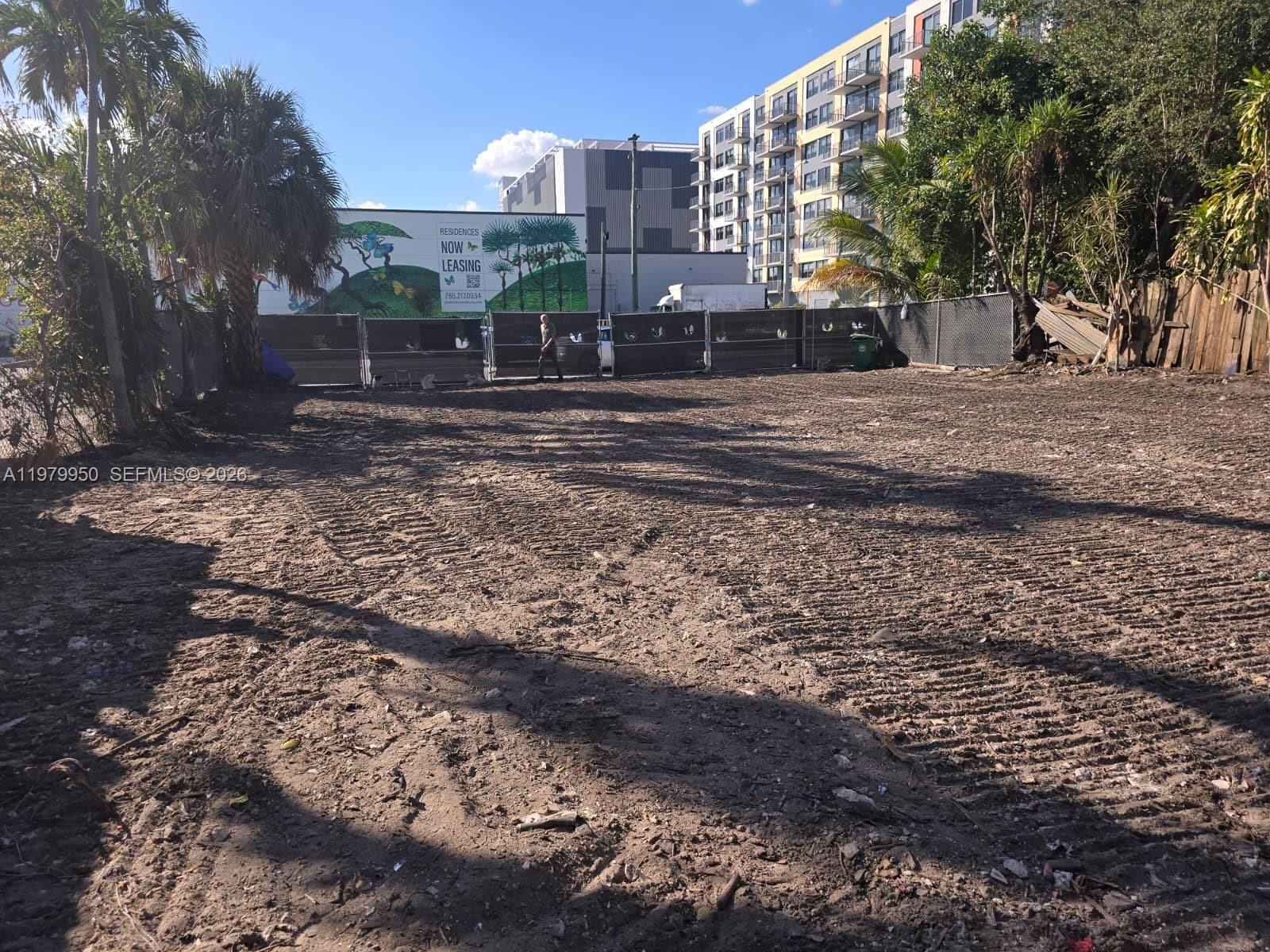 A vacant, dirt-covered lot is enclosed by a chain-link fence with a mural in the background — 951 NW 37th Ave, Miami FL 33125, MIAMI, FL