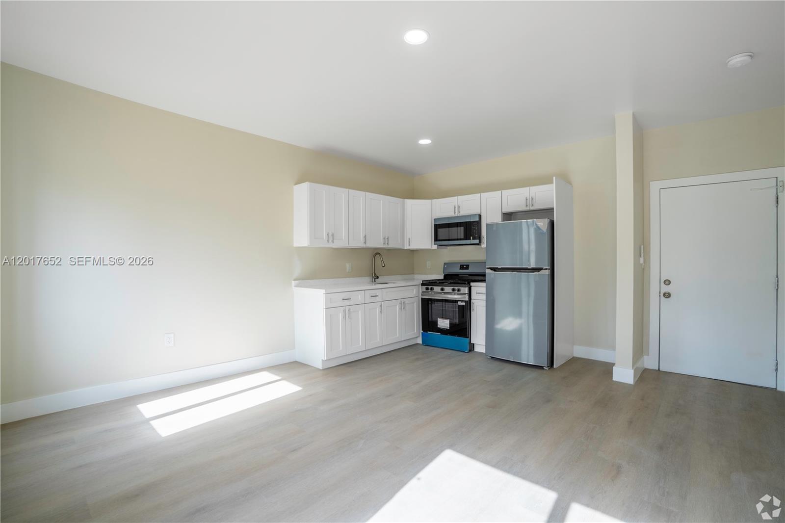 A kitchen features white cabinets, stainless steel appliances, and light wood flooring — 433 SW 6th St # 10, Miami FL 33130, MIAMI, FL