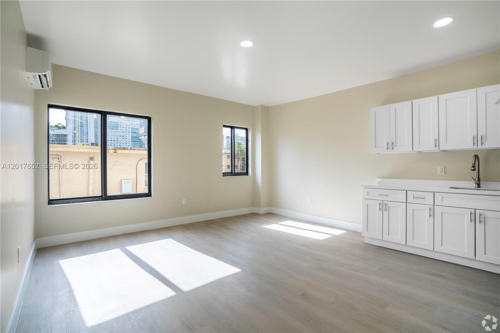 A bright room features light wood-look flooring, white cabinets, a sink, and two windows — 433 SW 6th St # 10, Miami FL 33130, MIAMI, FL
