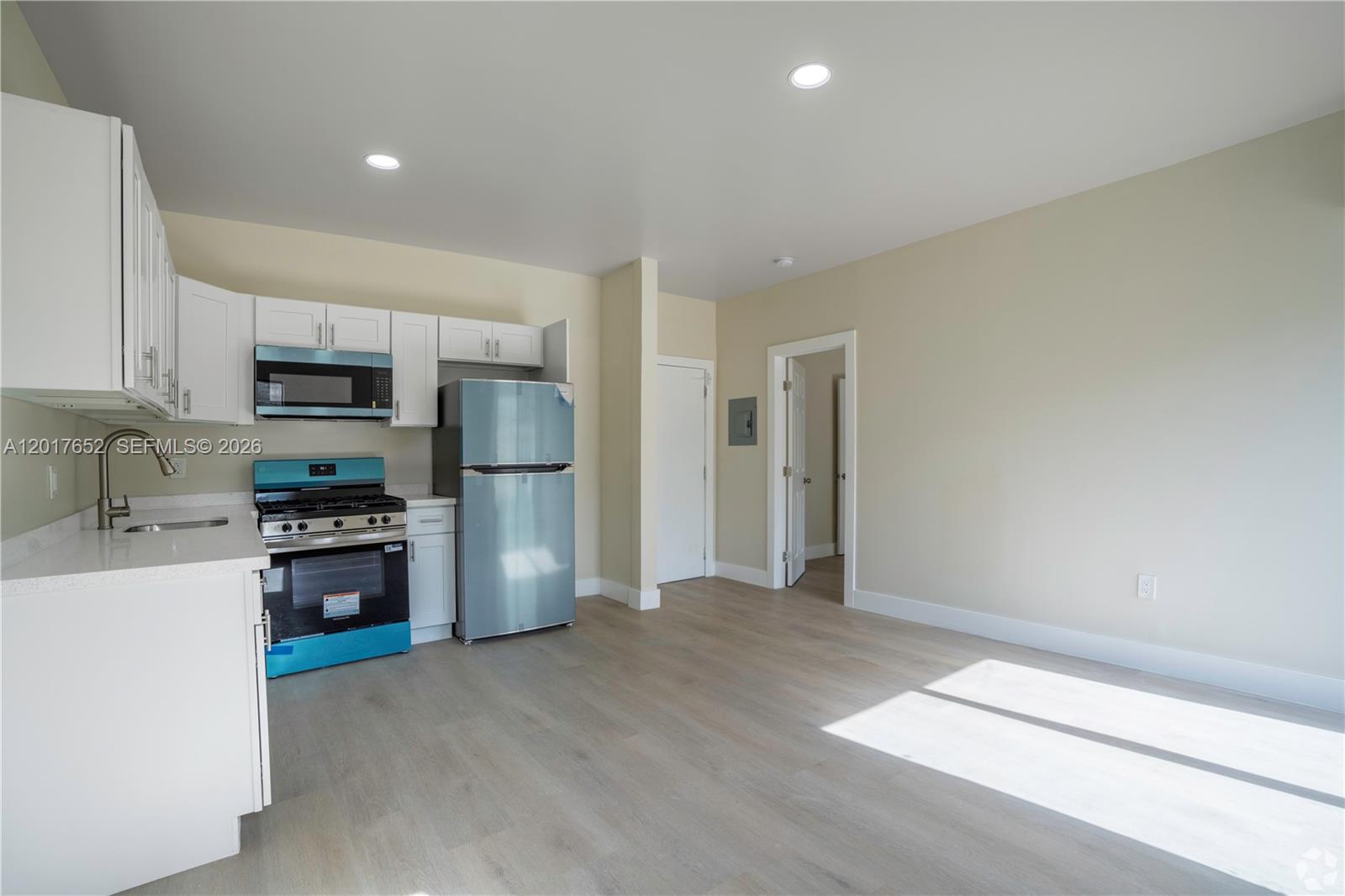 A kitchen features white cabinets, stainless steel appliances, and light wood-look flooring — 433 SW 6th St # 10, Miami FL 33130, MIAMI, FL
