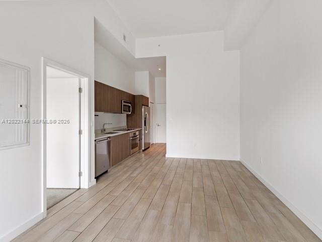 A modern kitchen with wood cabinets and stainless steel appliances opens into a living area — 1600 SW 1 Ave # 305, Miami FL 33129, MIAMI, FL