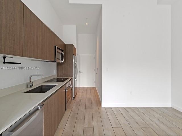 A modern kitchen features wood-toned cabinetry, stainless steel appliances, and light-colored tile flooring — 1600 SW 1 Ave # 305, Miami FL 33129, MIAMI, FL