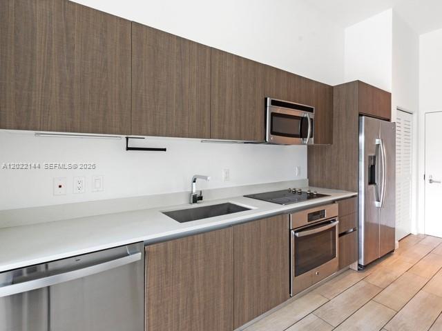 A modern kitchen features wood-grain cabinets, stainless steel appliances, and light-colored countertops — 1600 SW 1 Ave # 305, Miami FL 33129, MIAMI, FL
