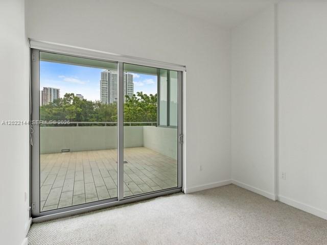 A room with beige carpeting features a large sliding glass door opening onto a balcony — 1600 SW 1 Ave # 305, Miami FL 33129, MIAMI, FL