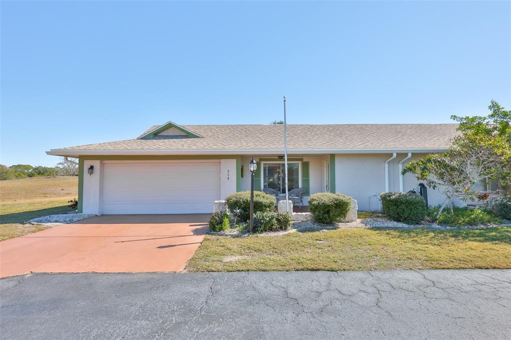 A single-story house with a white garage door, light-colored stucco walls, and a shingled roof — 318 FAIRSIDE COURT, SUN CITY CENTER, FL