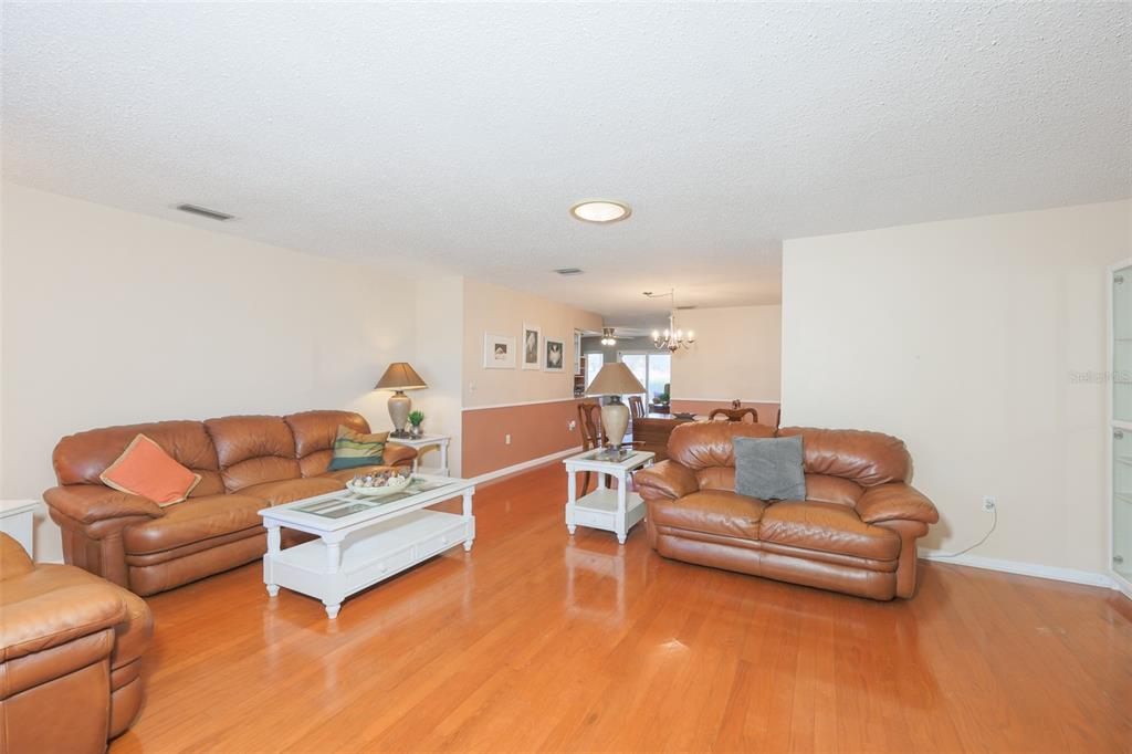 A living room features two brown leather sofas, a white coffee table, and hardwood floors — 318 FAIRSIDE COURT, SUN CITY CENTER, FL
