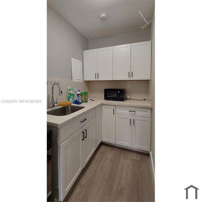 A small kitchen features white cabinets, light countertops, a stainless steel sink, and wood flooring — 3735 NW 21st Ct # 3735, Miami FL 33142, MIAMI, FL