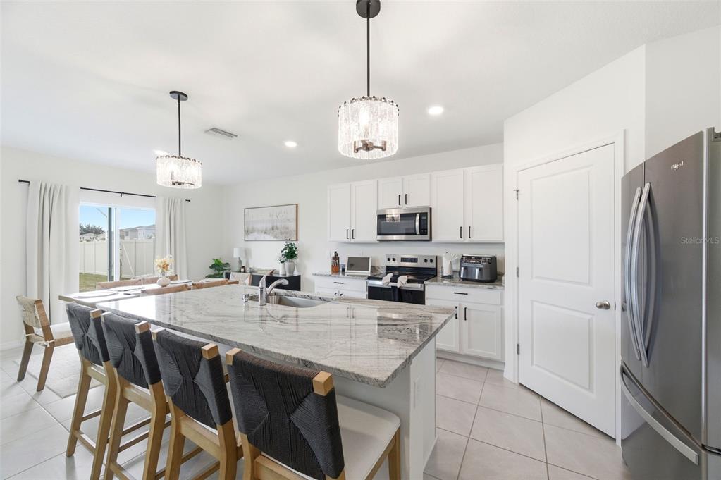 A kitchen features a large granite-topped island, white cabinetry, and stainless steel appliances — 8210 DOLPHIN BLUFF BOULEVARD, WESLEY CHAPEL, FL