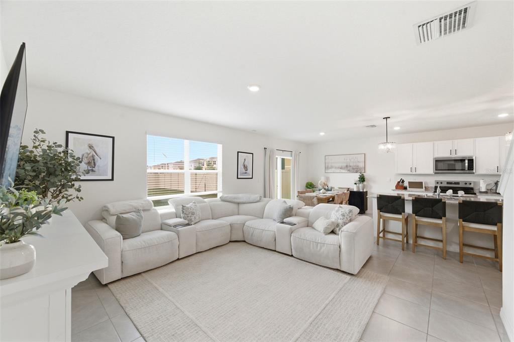 A white sectional sofa sits on a rug in an open-concept living room and kitchen — 8210 DOLPHIN BLUFF BOULEVARD, WESLEY CHAPEL, FL