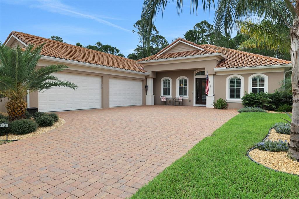 A single-story house with a tiled roof, a brick paver driveway, and a three-car garage — 142 PORTOFINO BLVD, NEW SMYRNA BEACH, FL