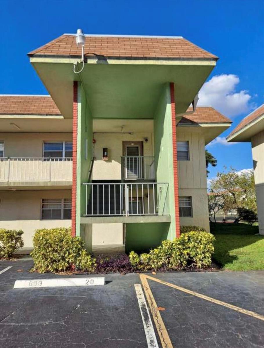 Exterior view of a two-story apartment building with a central staircase and green entryway — 603 S State Road 7 # 2i, Margate FL 33068, MARGATE, FL