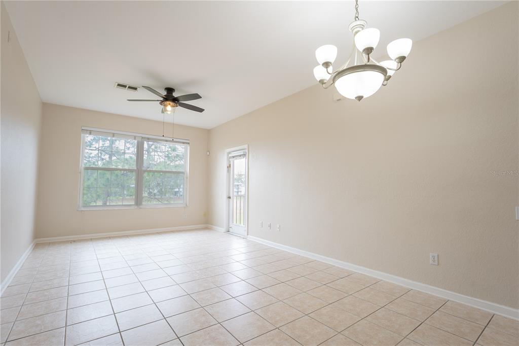 A bright room features light-colored tile flooring, a ceiling fan, and a chandelier — 13524 TURTLE MARSH LOOP UNIT 623, ORLANDO, FL