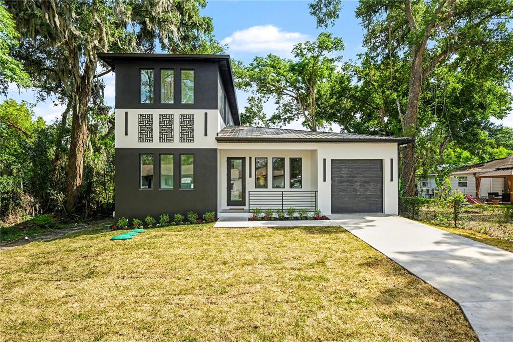 A two-story modern house with a dark gray exterior, white accents, and a concrete driveway — 105 GARLAND AVENUE, SEFFNER, FL