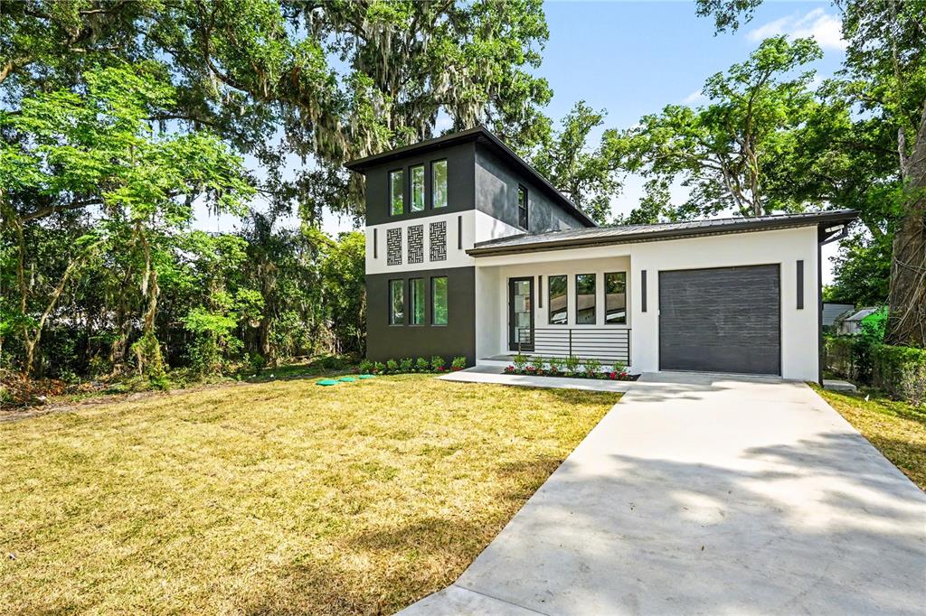 A modern two-story house with a dark gray exterior, white accents, and a concrete driveway — 105 GARLAND AVENUE, SEFFNER, FL