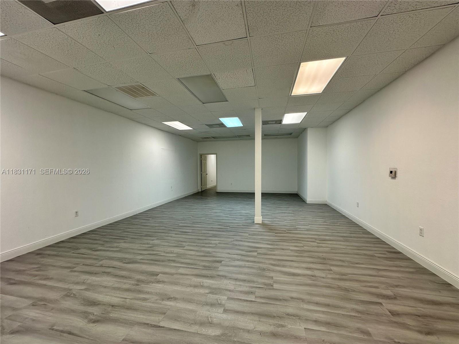 An empty office space features white walls, a drop ceiling, and gray wood-look flooring — 2922 N State Road 7 # 2920, Margate FL 33063, MARGATE, FL