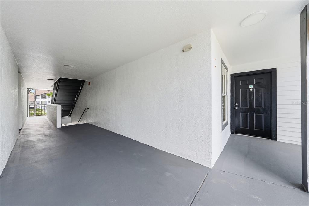 A covered outdoor entryway features a gray concrete floor, white walls, and a black door — 2201 KEY WEST COURT UNIT 328, KISSIMMEE, FL