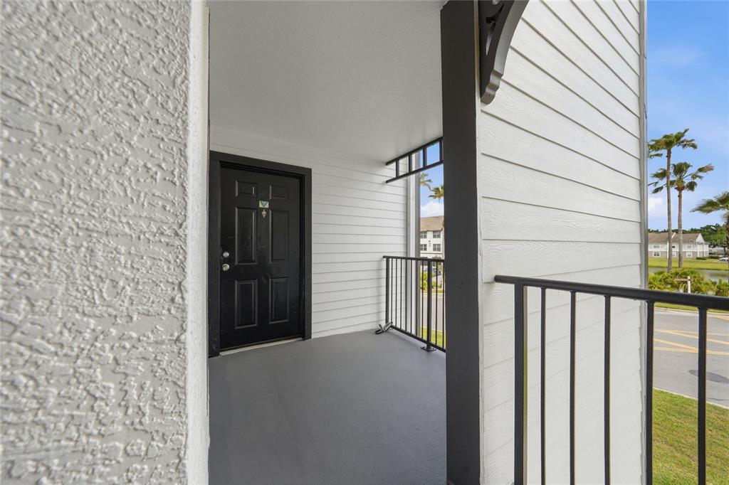 A covered balcony features a black door, gray flooring, and a black metal railing — 2201 KEY WEST COURT UNIT 328, KISSIMMEE, FL