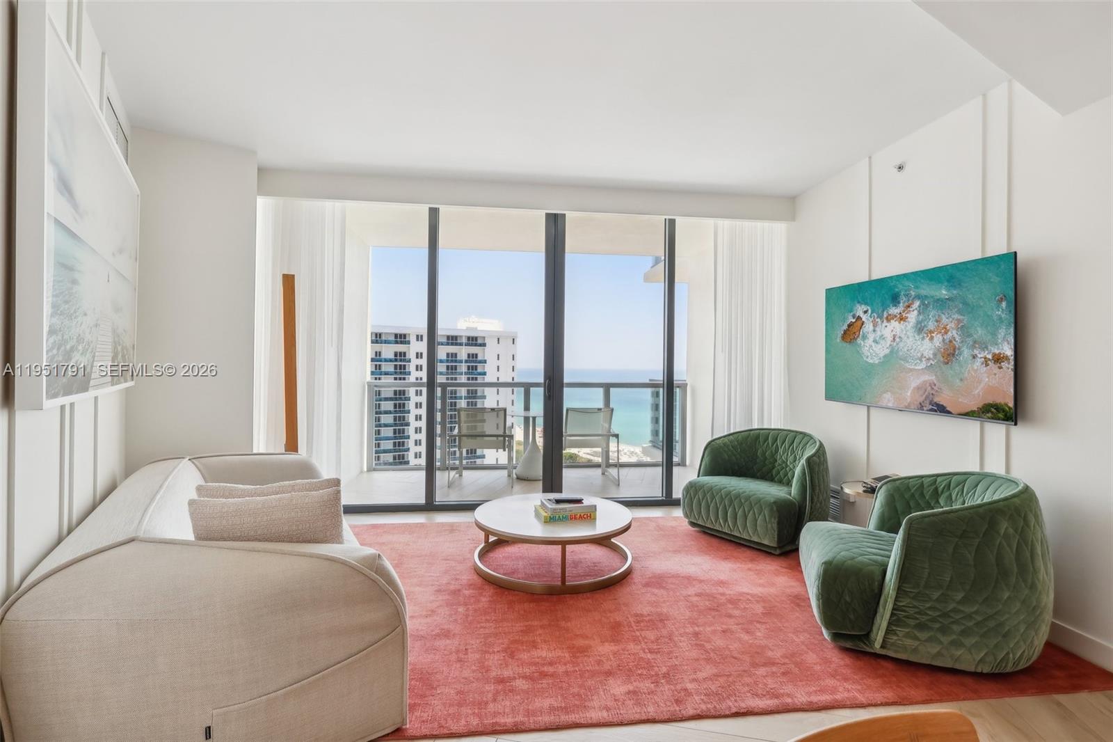A living room features a coral rug, two green armchairs, a sofa, and balcony views — 2201 Collins Ave # 1511, Miami Beach FL 33139, MIAMI BEACH, FL