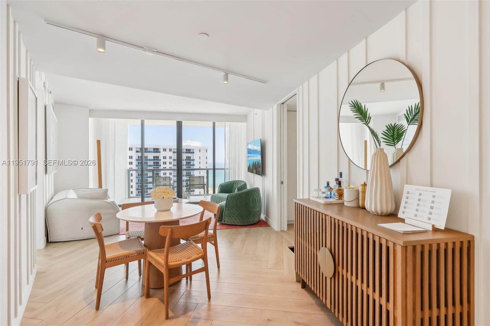 A modern dining area features a round table, wooden chairs, and a slatted sideboard — 2201 Collins Ave # 1511, Miami Beach FL 33139, MIAMI BEACH, FL