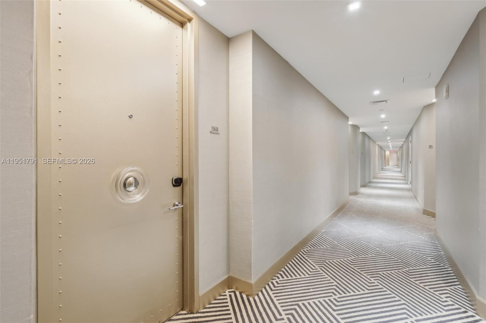 A long hotel hallway features a light-colored door with a circular handle and patterned carpeting — 2201 Collins Ave # 1511, Miami Beach FL 33139, MIAMI BEACH, FL