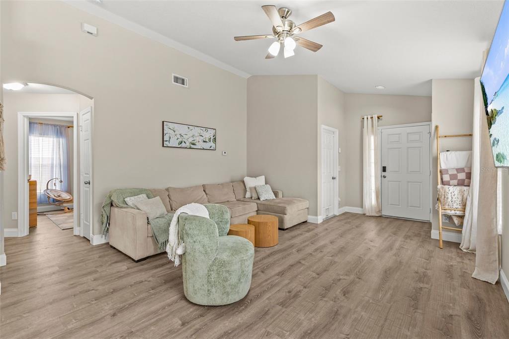 A living room features a beige sectional sofa, a green armchair, and wood-look flooring — 10611 LAKESIDE VISTA DRIVE, RIVERVIEW, FL