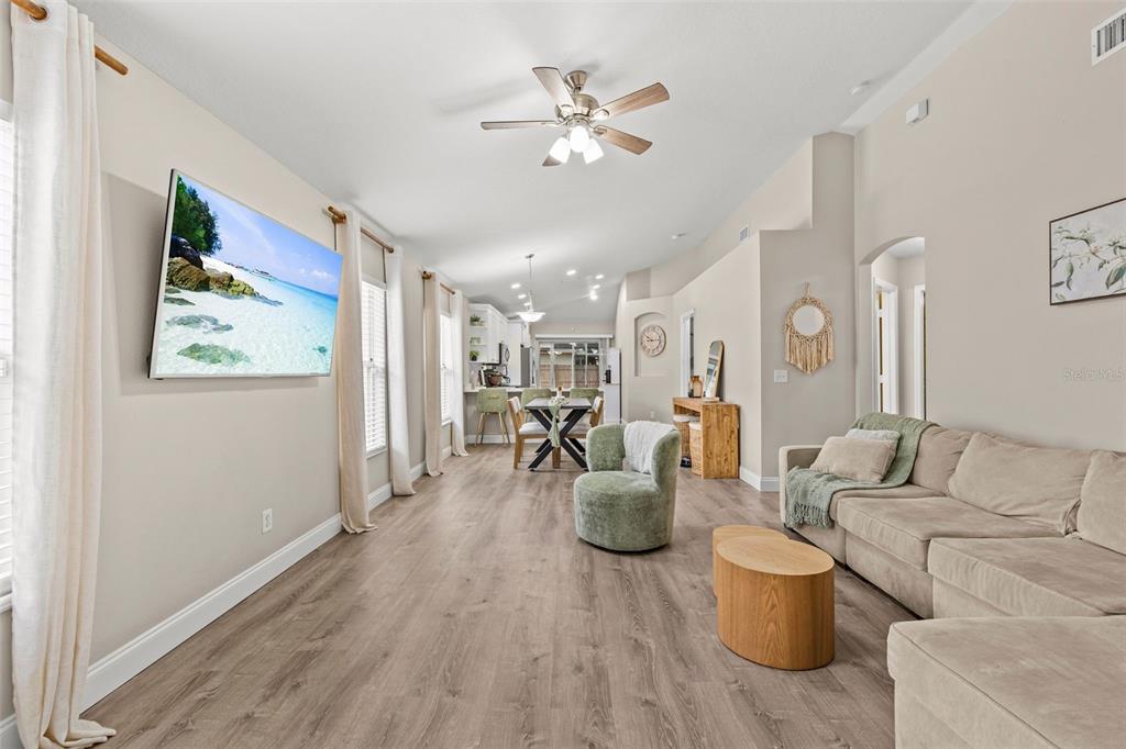 A living room and dining area feature light wood flooring, neutral walls, and a ceiling fan — 10611 LAKESIDE VISTA DRIVE, RIVERVIEW, FL
