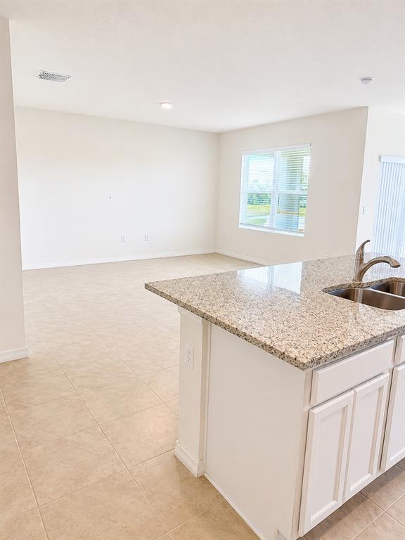 A kitchen island with granite countertops overlooks an open-concept living area with tile flooring — 1071 BROOKLET DRIVE, DAVENPORT, FL
