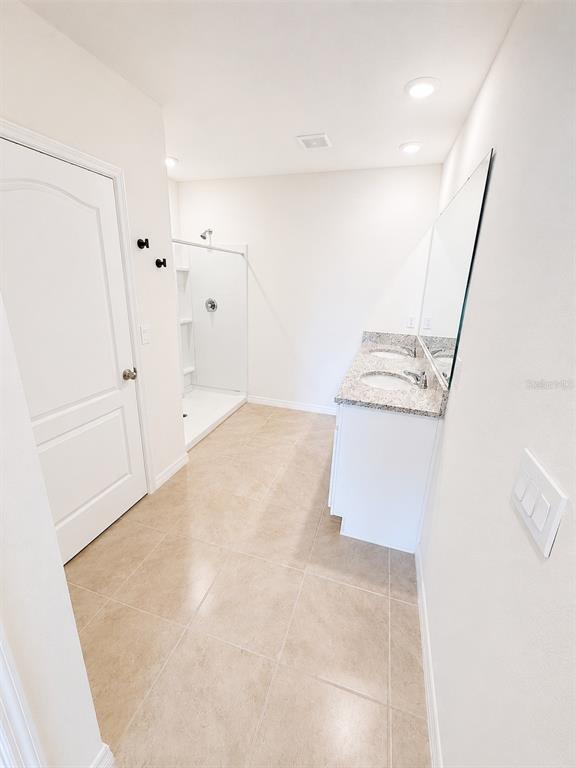 A bathroom features a double vanity with granite countertops, a walk-in shower, and tile flooring — 1071 BROOKLET DRIVE, DAVENPORT, FL