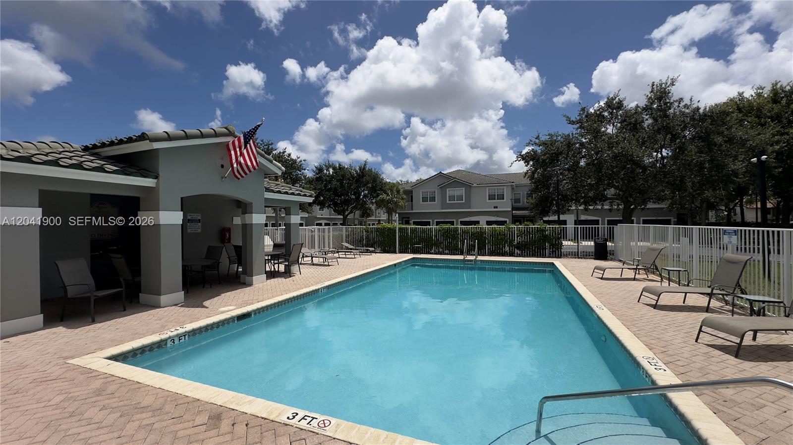 A rectangular swimming pool is surrounded by a brick patio and lounge chairs — 3042 Grandiflora Dr, Green Acres FL 33467, GREEN ACRES, FL