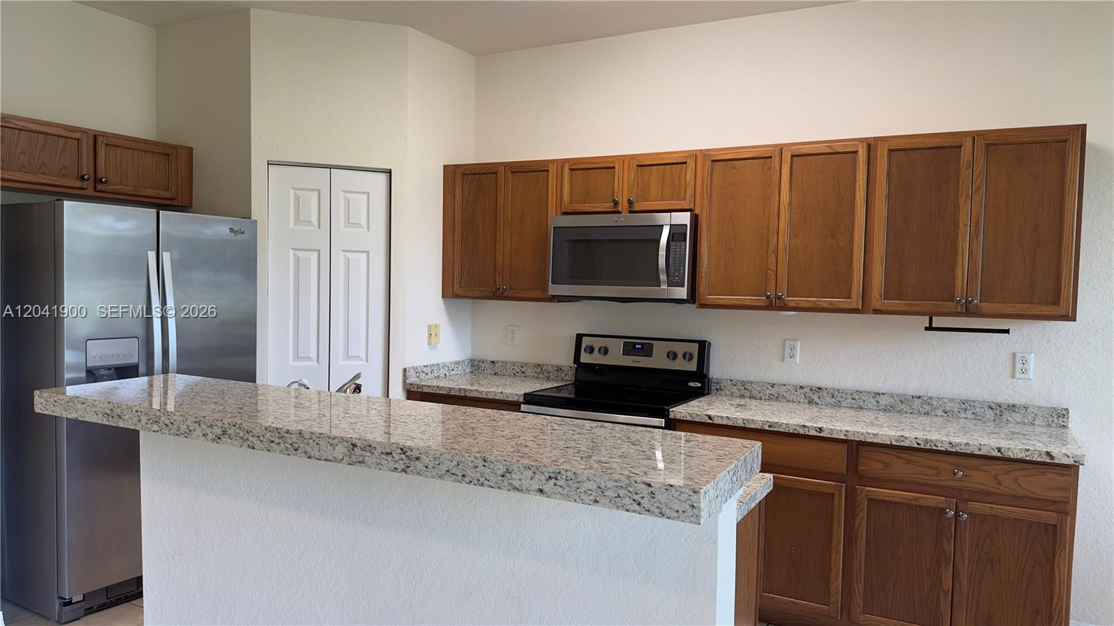 A kitchen features oak cabinets, granite countertops, and stainless steel appliances — 3042 Grandiflora Dr, Green Acres FL 33467, GREEN ACRES, FL