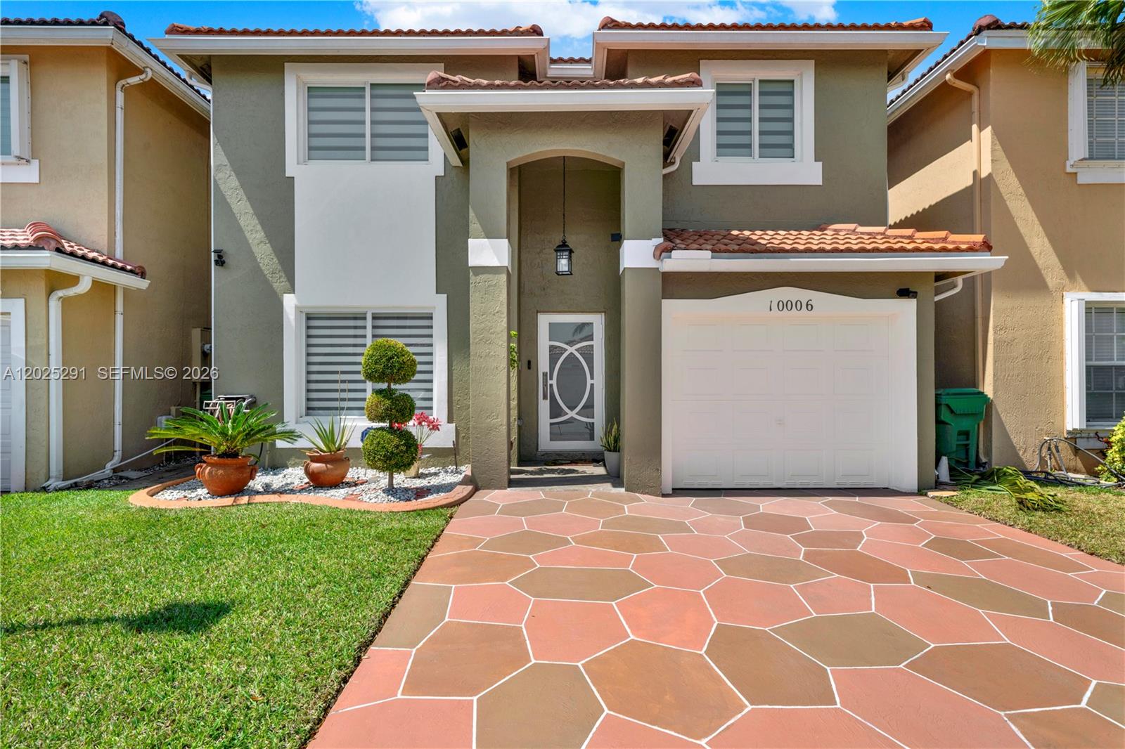 A two-story house features a paved driveway, a white garage door, and a covered entryway — 10006 SW 162nd Path, Miami FL 33196, MIAMI, FL
