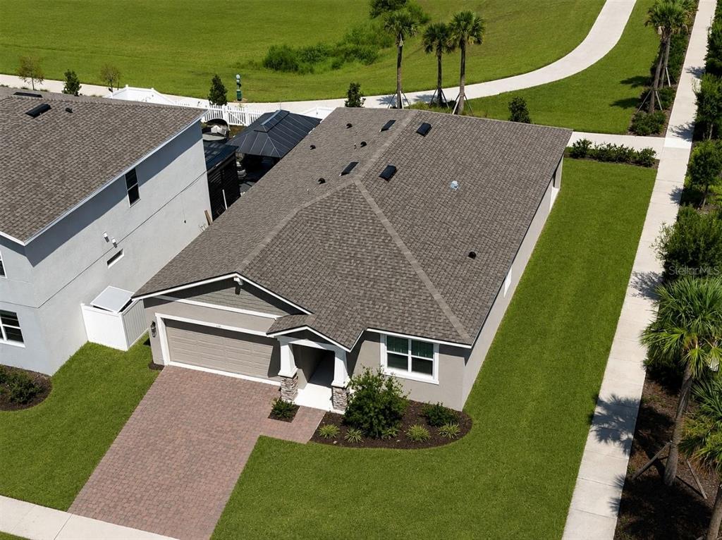 An aerial view of a single-story house with a gray roof and paved driveway — 1141 LAKESHORE BREEZE PLACE, KISSIMMEE, FL