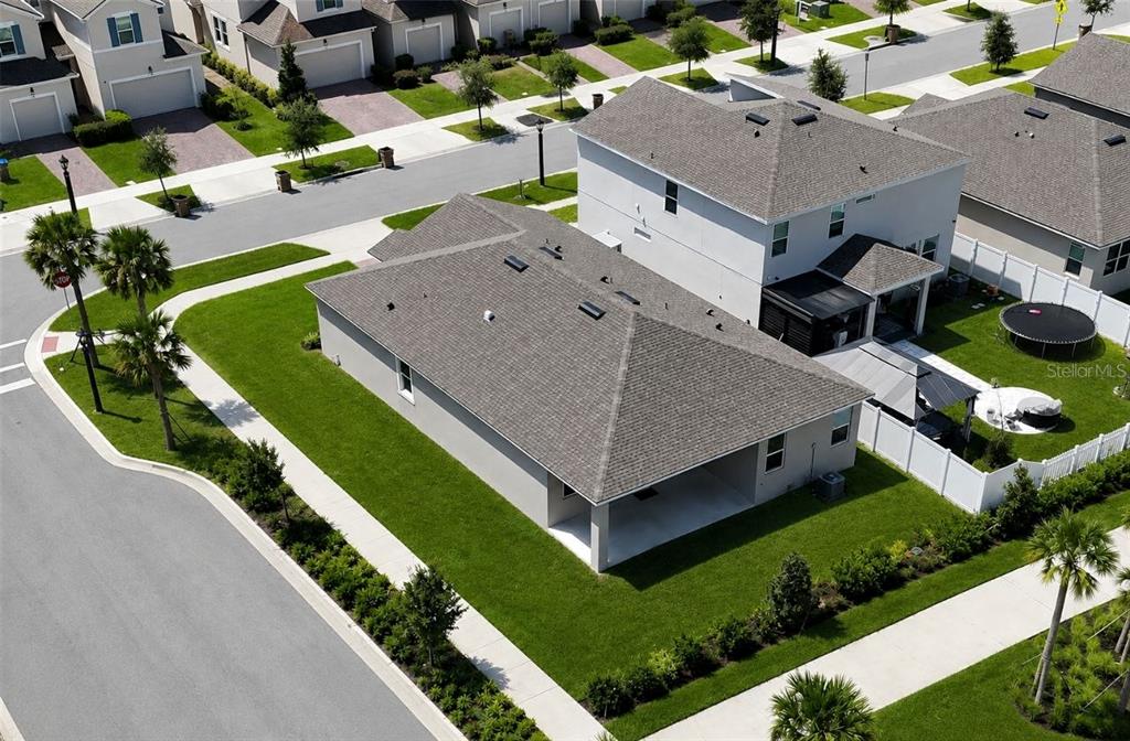 An aerial view shows a suburban house with a gray roof and a backyard lawn — 1141 LAKESHORE BREEZE PLACE, KISSIMMEE, FL