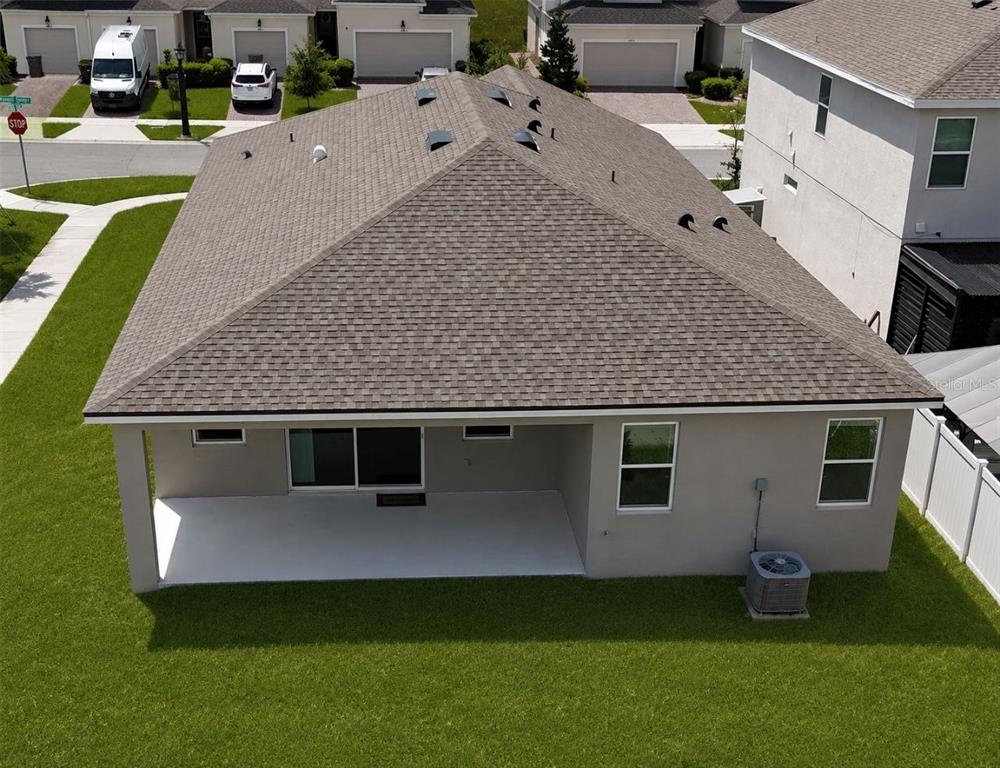 An aerial view of a house exterior showing a shingled roof and a covered patio — 1141 LAKESHORE BREEZE PLACE, KISSIMMEE, FL