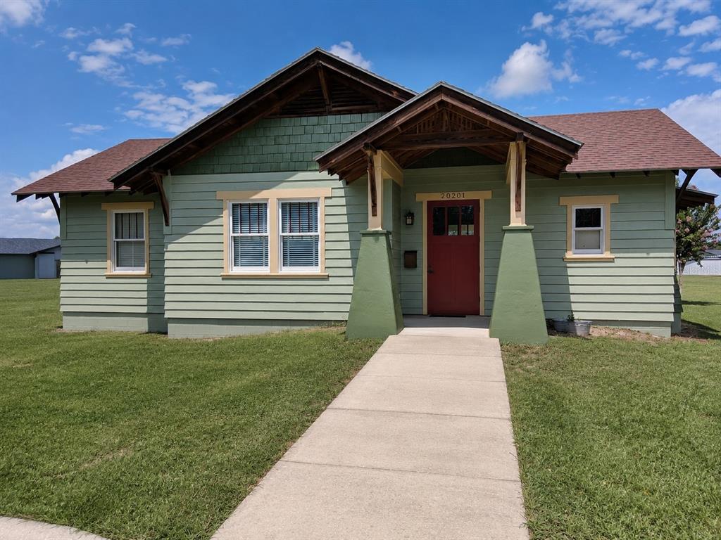 A light green, single-story bungalow with a red front door and a concrete walkway — GRASS ROOTS ROAD, GROVELAND, FL