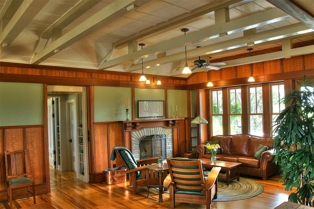 A living room features wood-paneled walls, a stone fireplace, exposed ceiling beams, and hardwood floors — GRASS ROOTS ROAD, GROVELAND, FL