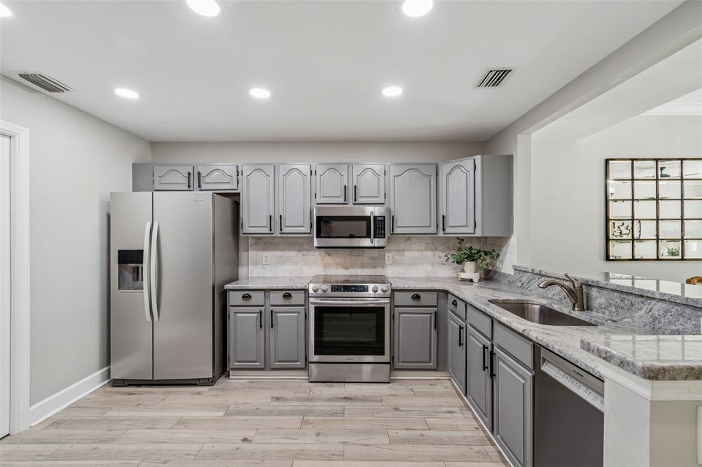 A kitchen features gray cabinets, stainless steel appliances, and granite countertops — 1508 S BAY VILLA PLACE UNIT B, TAMPA, FL