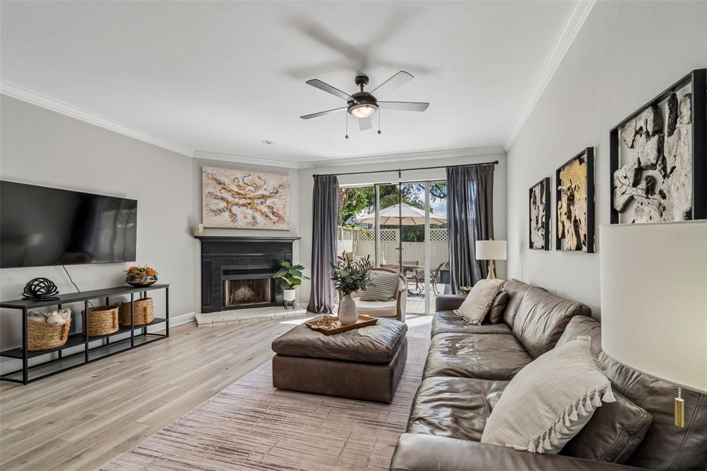 A living room features a fireplace, leather sectional, ceiling fan, and sliding glass patio doors — 1508 S BAY VILLA PLACE UNIT B, TAMPA, FL