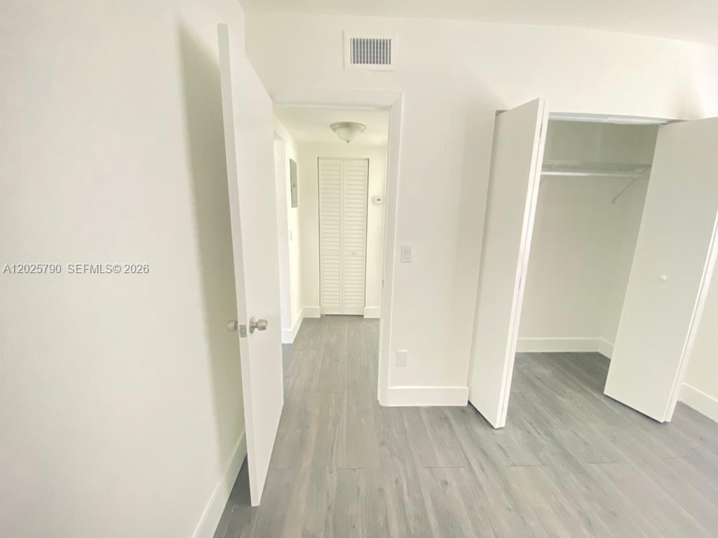 A hallway with light wood-look flooring leads to a closet with white louvered doors — 2150 NW 24th St # 2, Miami FL 33142, MIAMI, FL