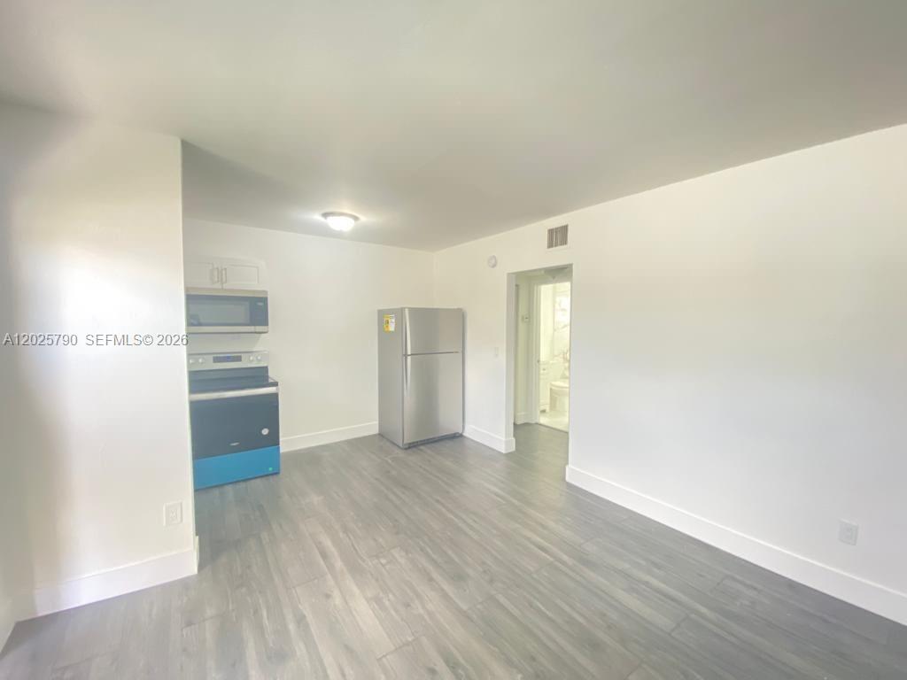 A kitchen area features stainless steel appliances, white walls, and gray wood-look flooring — 2150 NW 24th St # 2, Miami FL 33142, MIAMI, FL