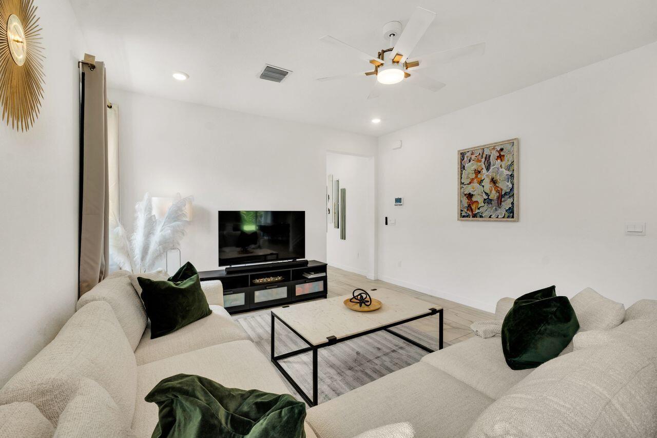 A kitchen and dining area features gray cabinets, a white island with stools, and tile floors — 4506 Catalina Way, FL 33463, FL