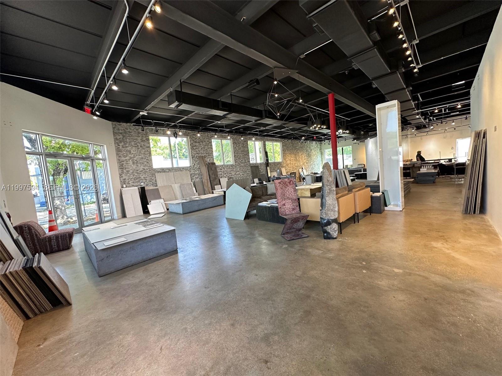 A spacious showroom features concrete floors, exposed black ceilings, and various stone tile displays — 280 NE 59th St # 290, Miami FL 33137, MIAMI, FL