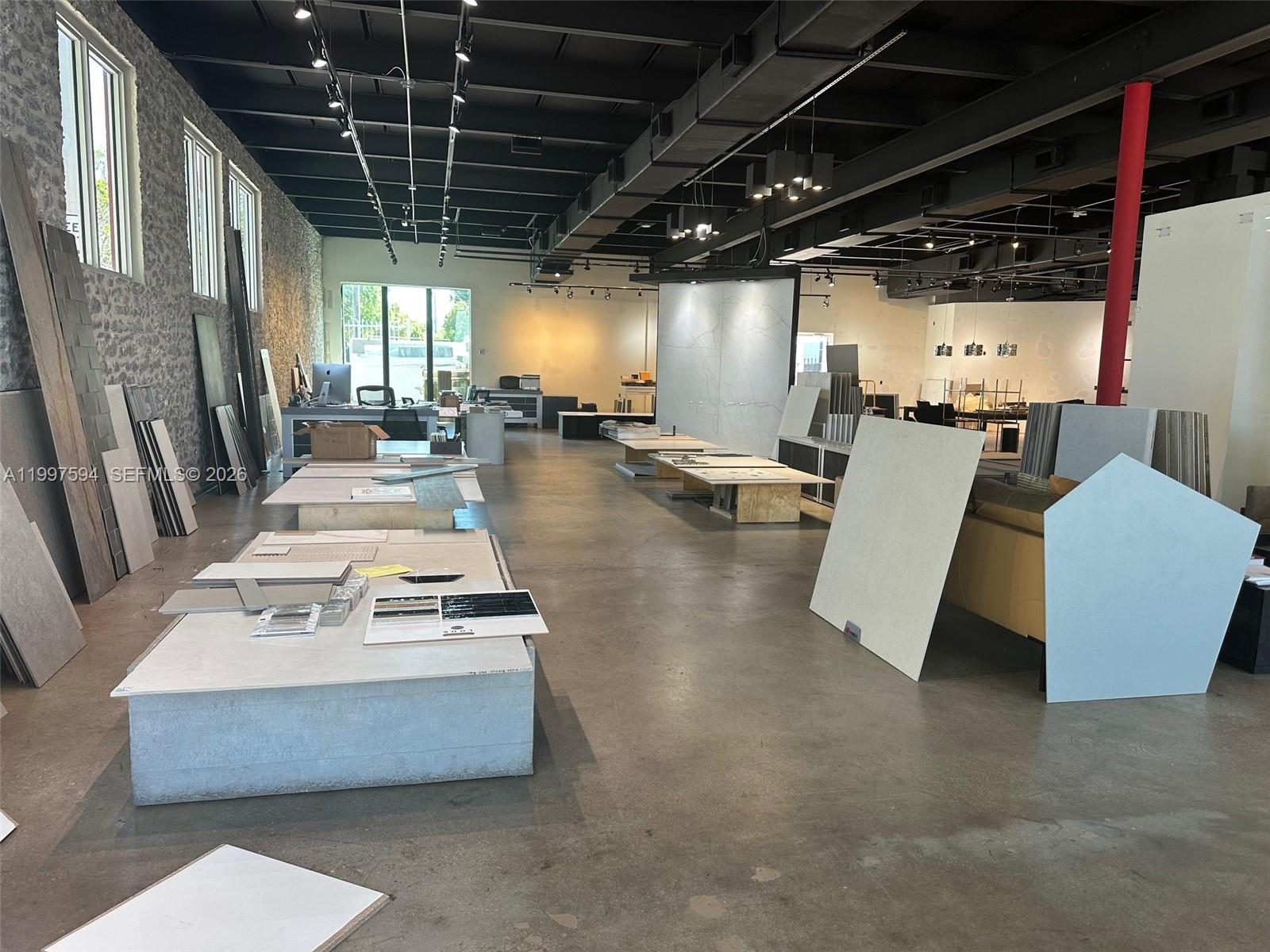 A commercial showroom features concrete floors, exposed ceilings, and various tile and stone displays — 280 NE 59th St # 290, Miami FL 33137, MIAMI, FL
