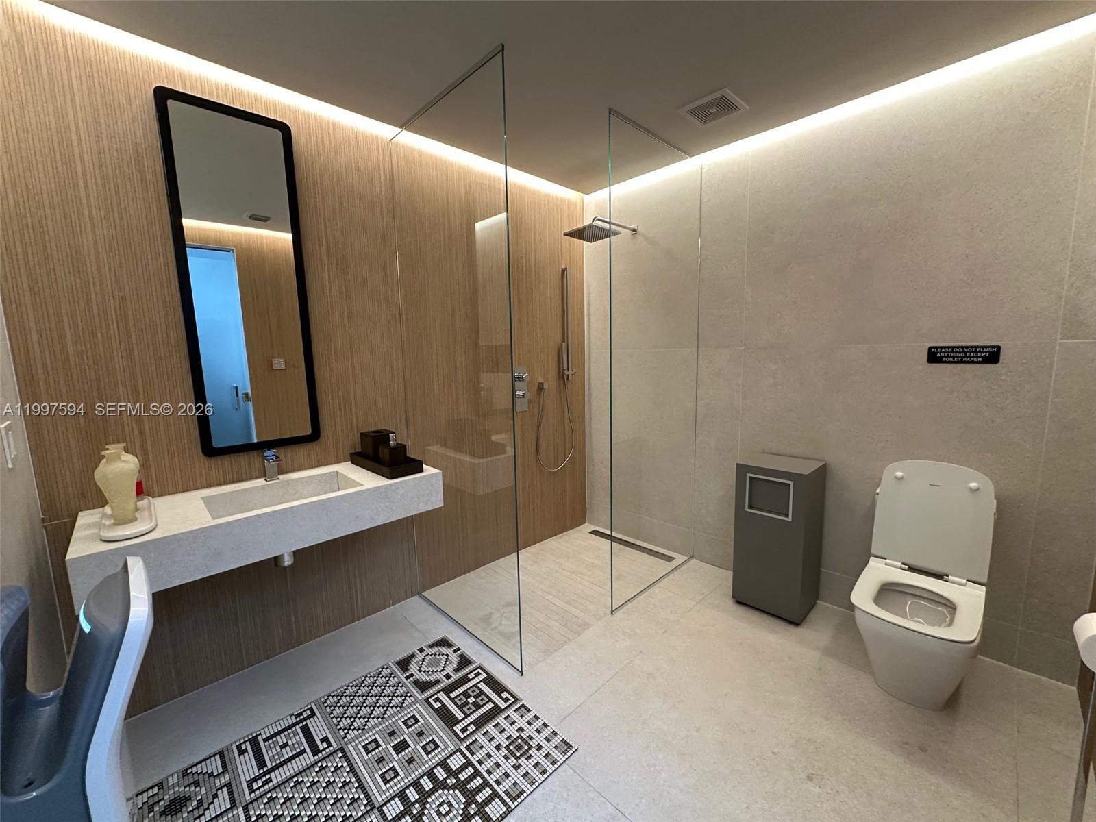 A modern bathroom features a floating vanity, glass-enclosed shower, and a toilet on tiled floors — 280 NE 59th St # 290, Miami FL 33137, MIAMI, FL