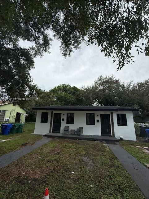 A single-story white house with a flat roof and two front doors sits on grass — 1786 NW 53rd St, Miami FL 33142, MIAMI, FL
